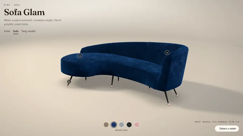Granatowa welurowa sofa w jasnym studiu, pod nią próbki kolorów obicia